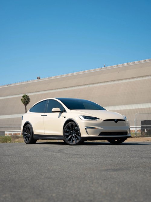 Tesla Model X with a pale yellow body finish in a full front three-quarter view