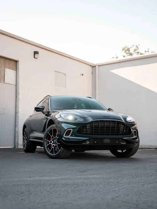 Dark green Aston Martin DBX in a complete front three-quarter view beside the studio building