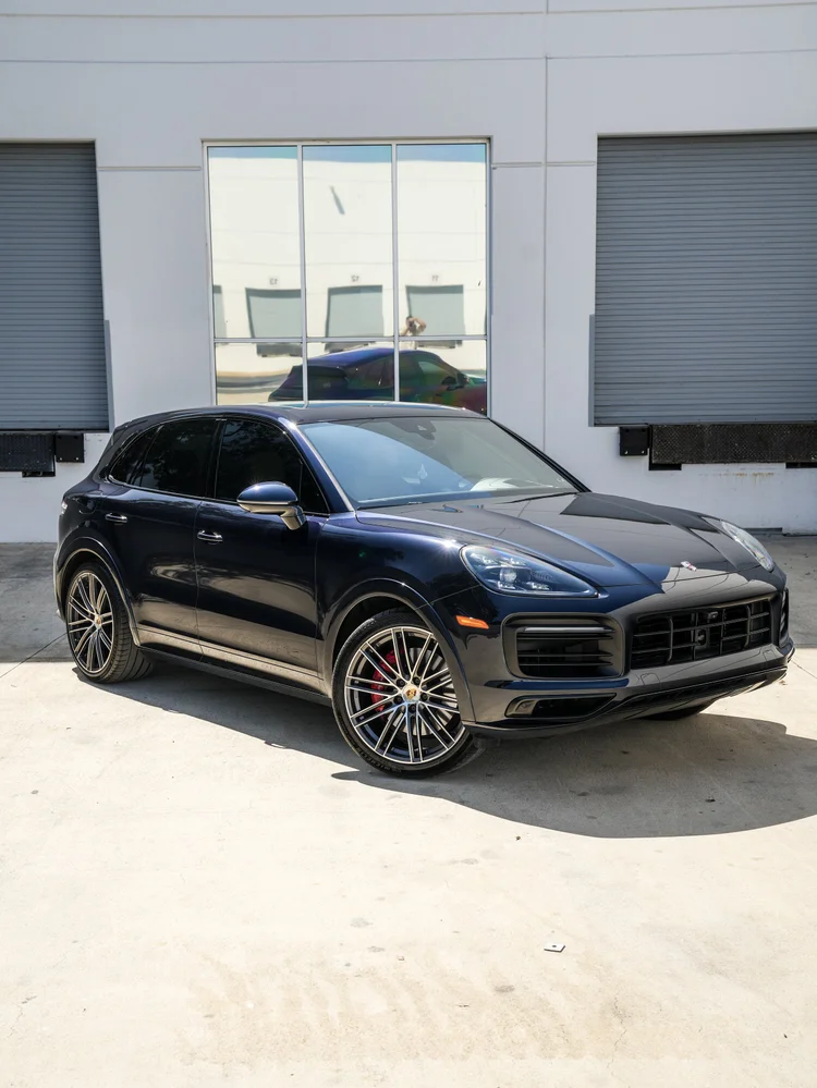 Complete front three-quarter view of a separate dark blue Porsche Cayenne GTS with silver multi-spoke wheels and red calipers.