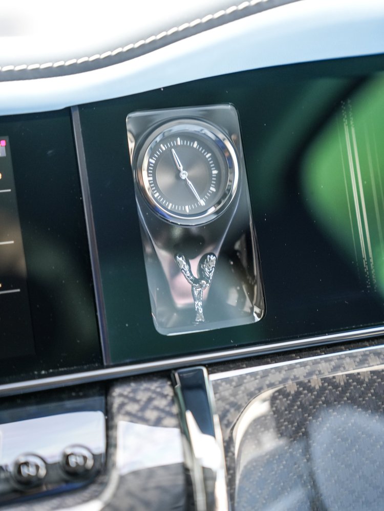 Analog clock and sculpted figure within the Cullinan glass-fronted dark dashboard display