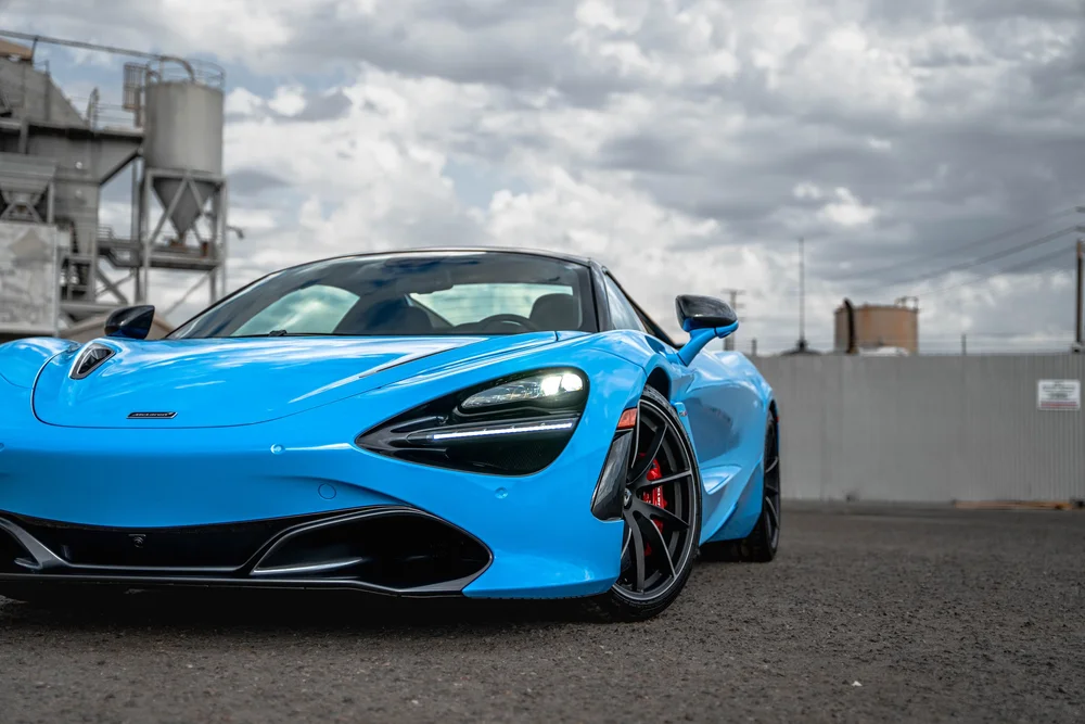 Low close front three-quarter view of the blue 720S with its headlight, front wheel and dark lower aero trim