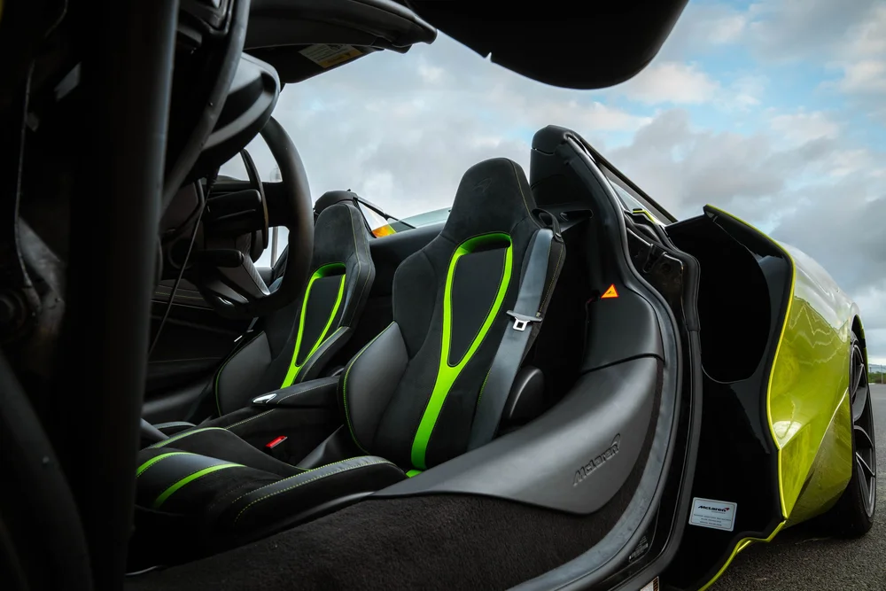 McLaren 720S black seats with green accents, steering wheel and open door