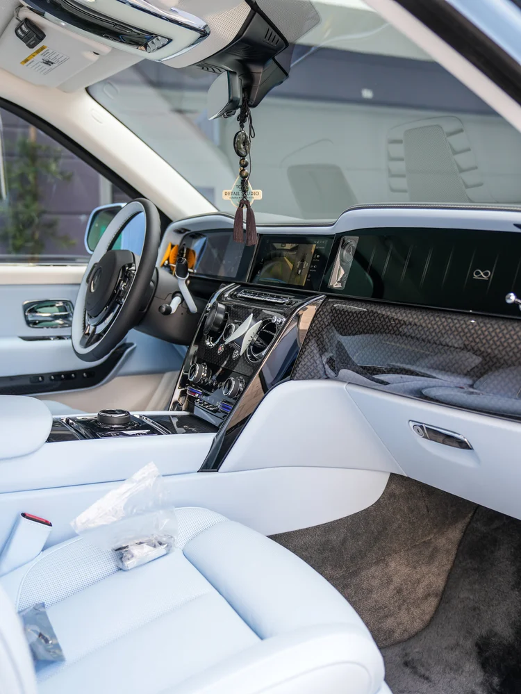 Cullinan dashboard, center console and pale blue front seat viewed through the open passenger door