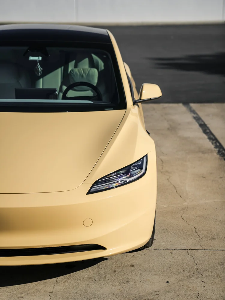 Tesla Model 3 in gloss Sunrise Yellow vinyl wrap, hood, headlight and front-bumper detail