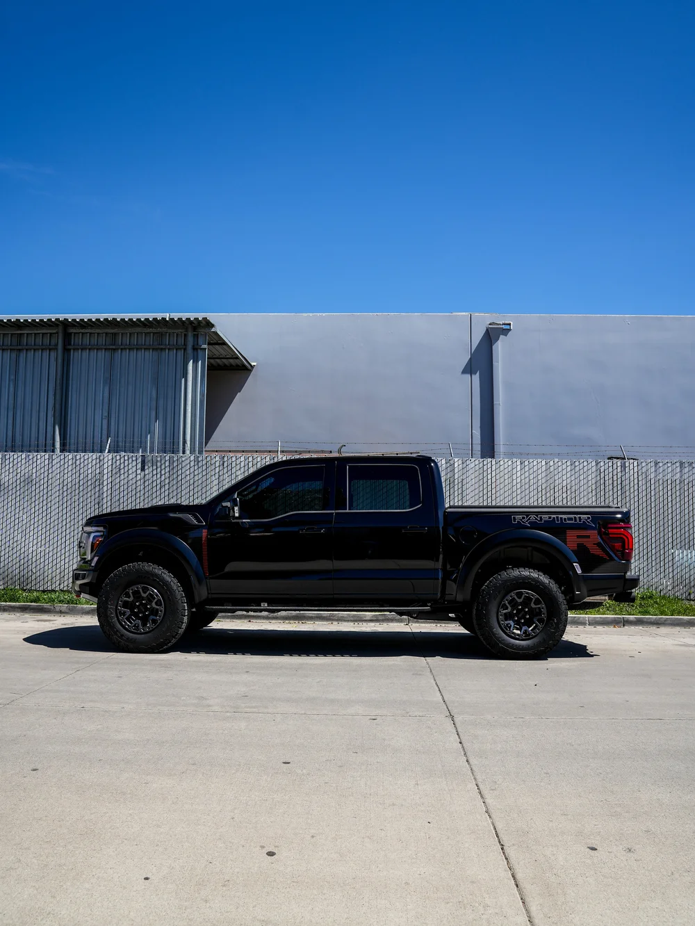 Full side profile of the black Ford F-150 Raptor R with bedside graphics and off-road tires.
