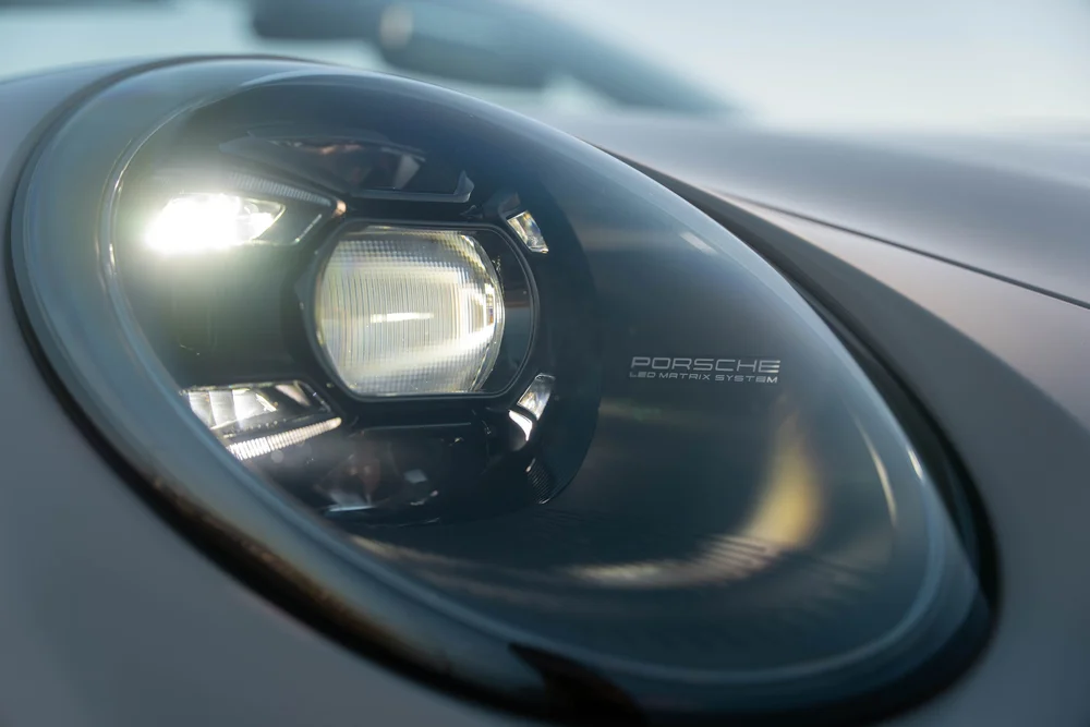 Chalk Porsche 911 Turbo S, illuminated round front headlight close-up