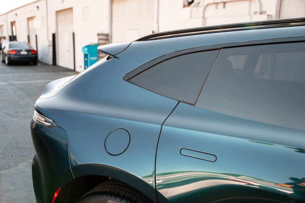 Green rear quarter with dark side glass, flush door handle and fuel door.