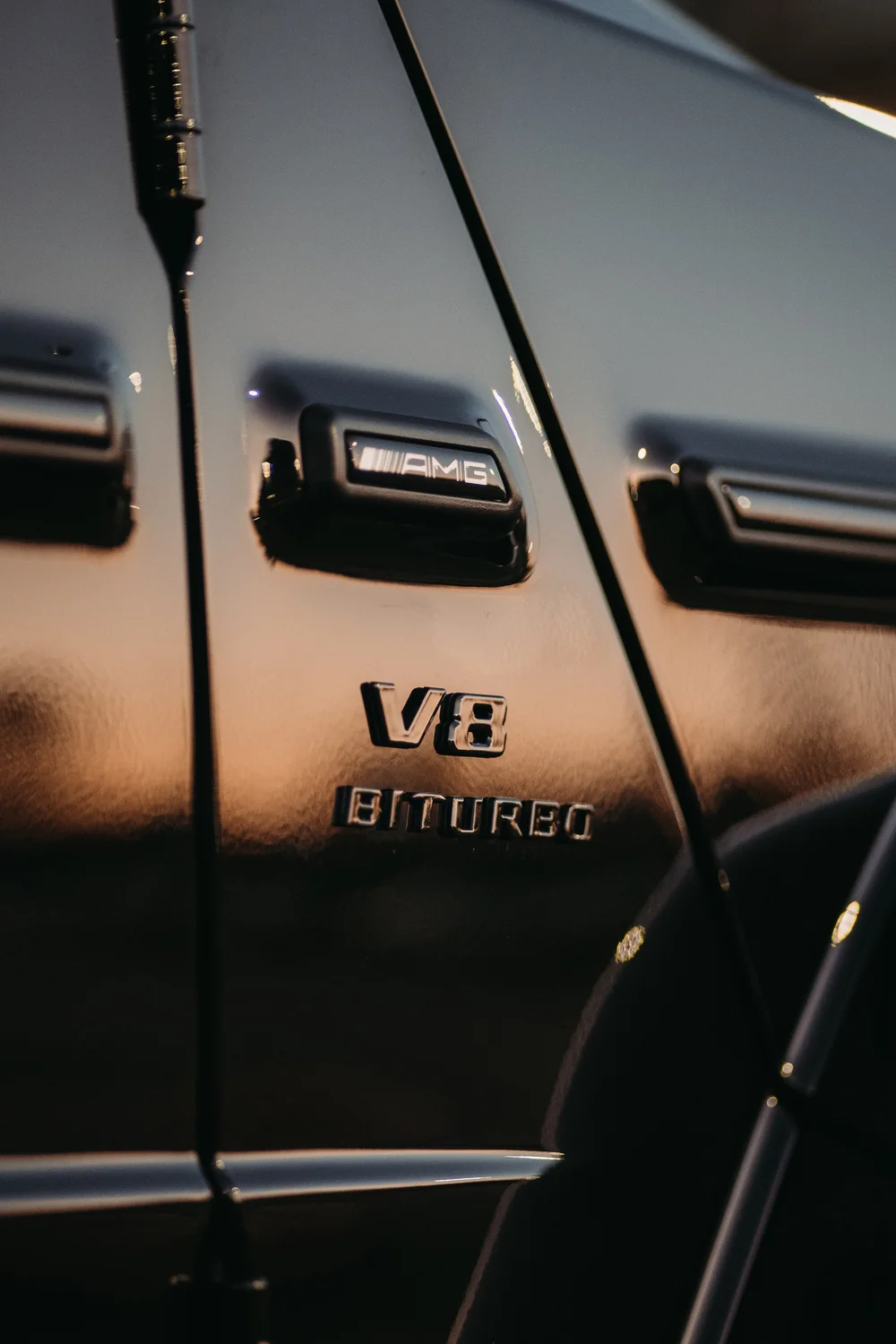 AMG plaque and visible V8 BITURBO lettering on the reflective dark fender between the door seam and wheel arch.