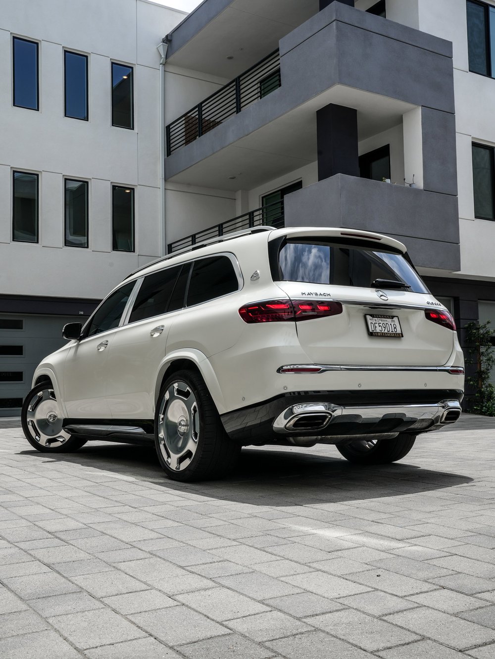 Complete rear three-quarter view of the white Mercedes-Maybach GLS 600 with red lamps, polished wheels and chrome bumper trim.