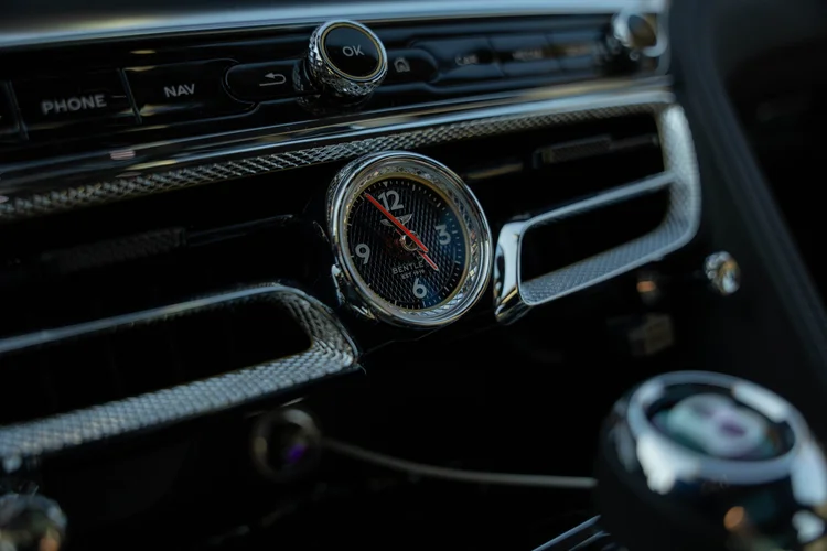 Round dashboard clock set within patterned trim beside the center air vents.