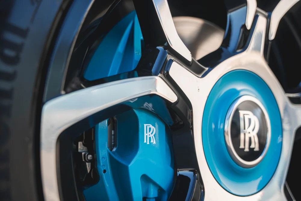 White Rolls-Royce Cullinan — close turquoise wheel-center and brake-caliper details