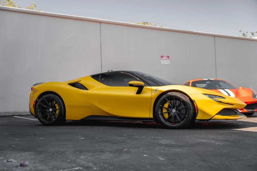 Full side profile of the yellow Ferrari SF90 with black roof, dark side glass, black wheels and side air intake