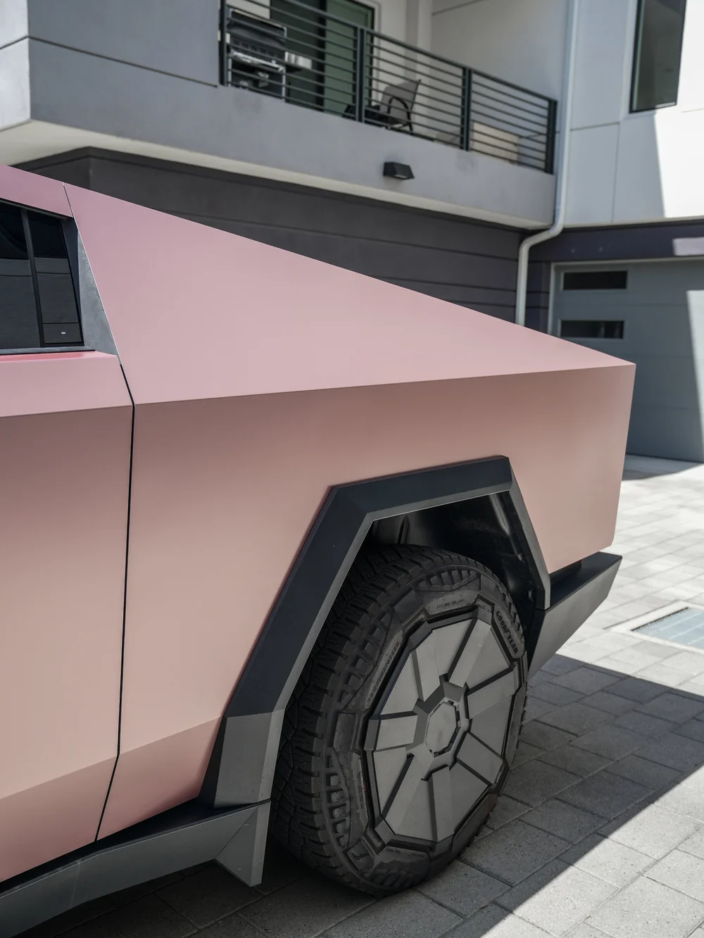 Pink-gold rear side-panel detail above a dark angular wheel cover, tire and black wheel-arch trim.