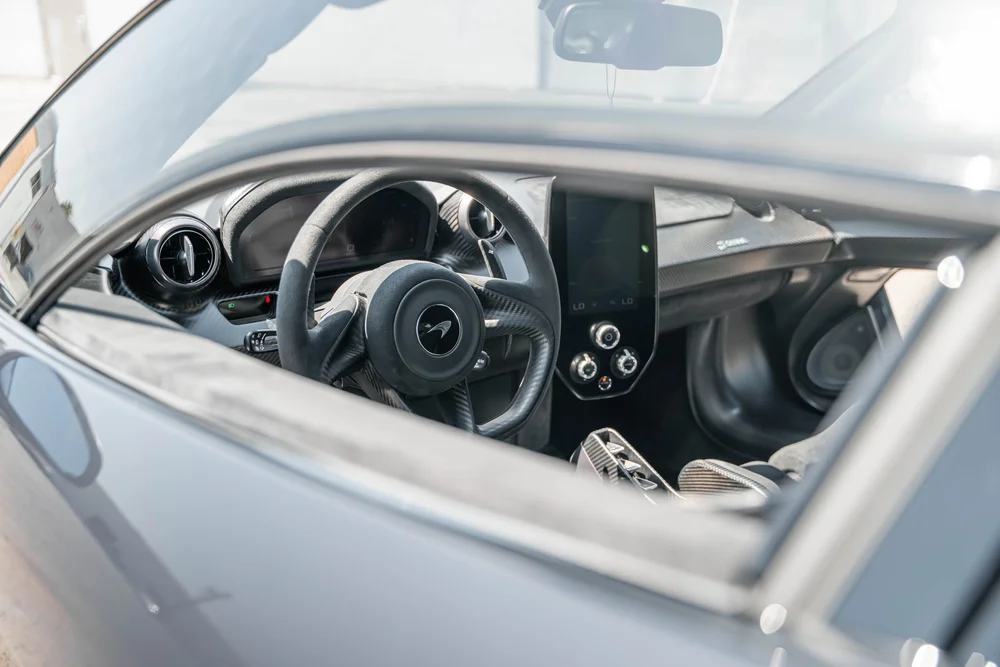 McLaren Senna steering wheel, round air vents and central display viewed through the side window