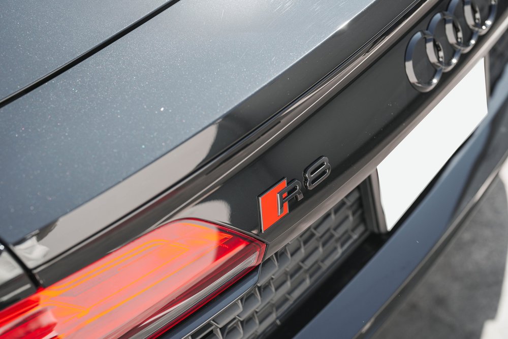 Rear R8 badge and Audi rings beside the red taillight and dark rear grille