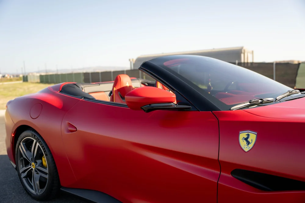 Red Ferrari Portofino mirror, windshield, fender shield and door contours beside the open red cabin