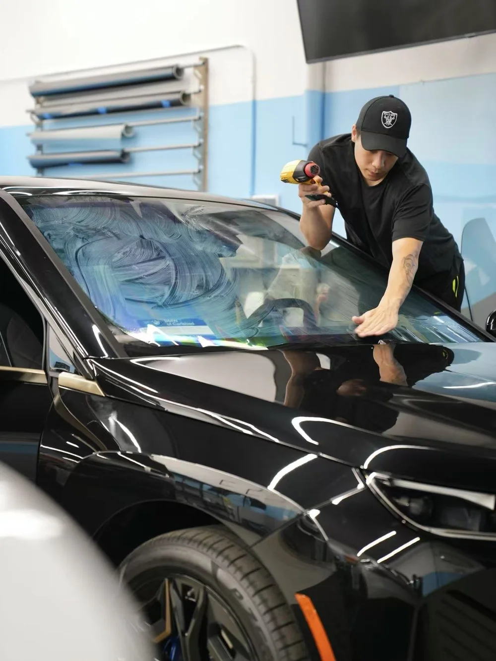 Technician installing windshield film in the Toyz Detail Studio shop.