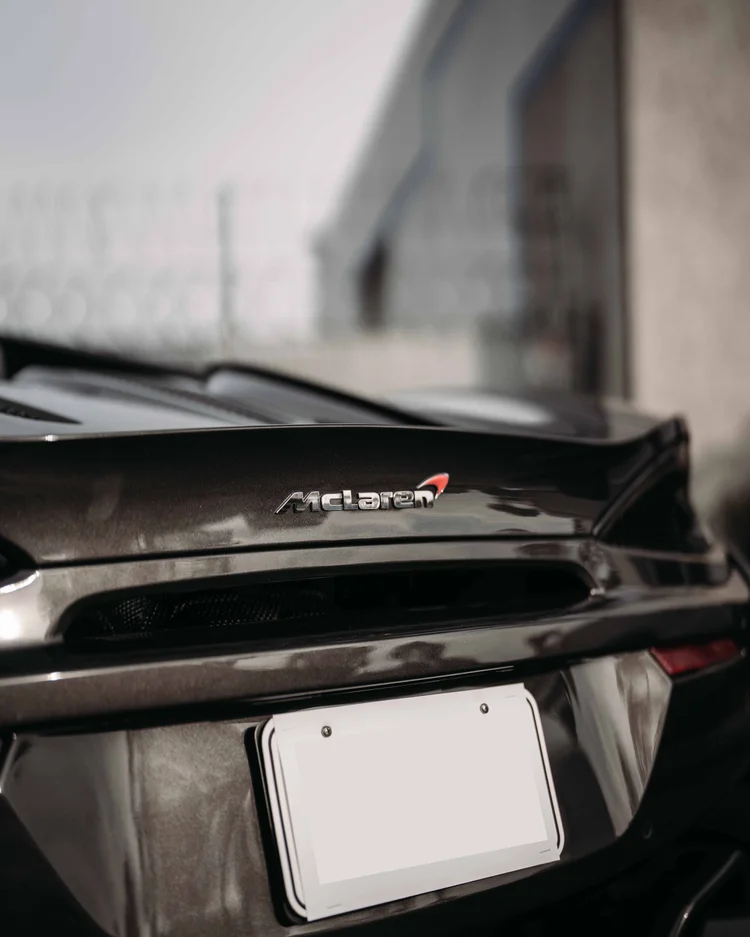 Rear McLaren wordmark above the central opening and pale license plate.