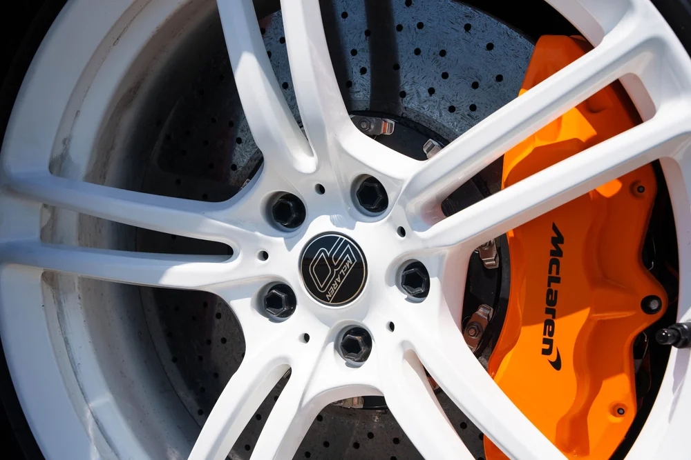 McLaren MP4-12C — close white wheel, orange brake caliper and visible brake disc
