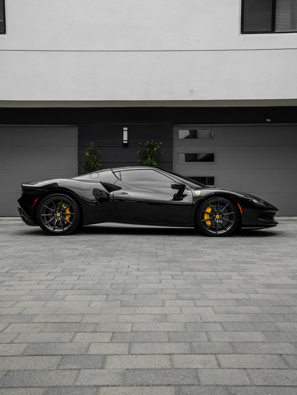 Full side profile of the black Ferrari 296 GTB outside the studio