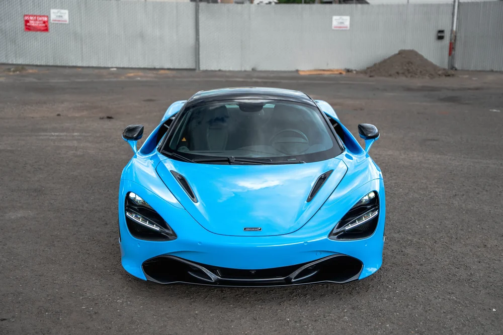 Elevated front view of the blue 720S hood, windshield and dark lower bumper