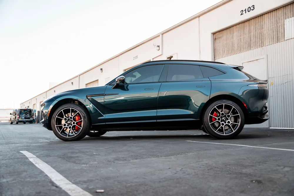 Full side profile of the green SUV with red brake calipers and a roof spoiler.