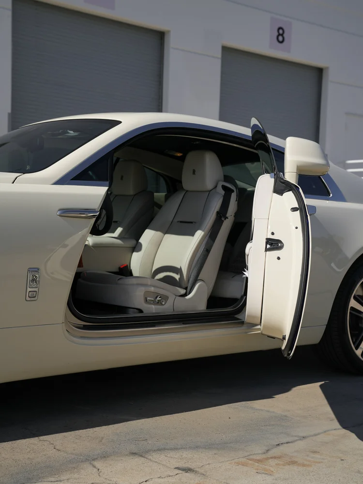 Open Rolls-Royce Wraith door and light front seat viewed from the opposite side of the cabin.