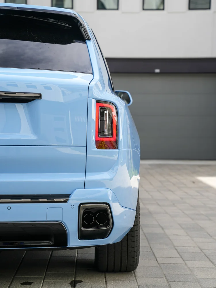 Powder Blue Cullinan rear corner with a vertical red taillight, dark bumper trim and paired exhaust outlets