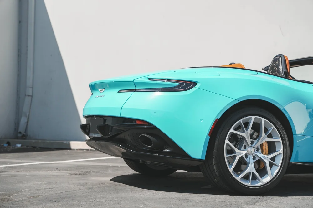 Miami Blue DB11 rear quarter with silver wheel, yellow brake caliper, taillamp and black exhaust