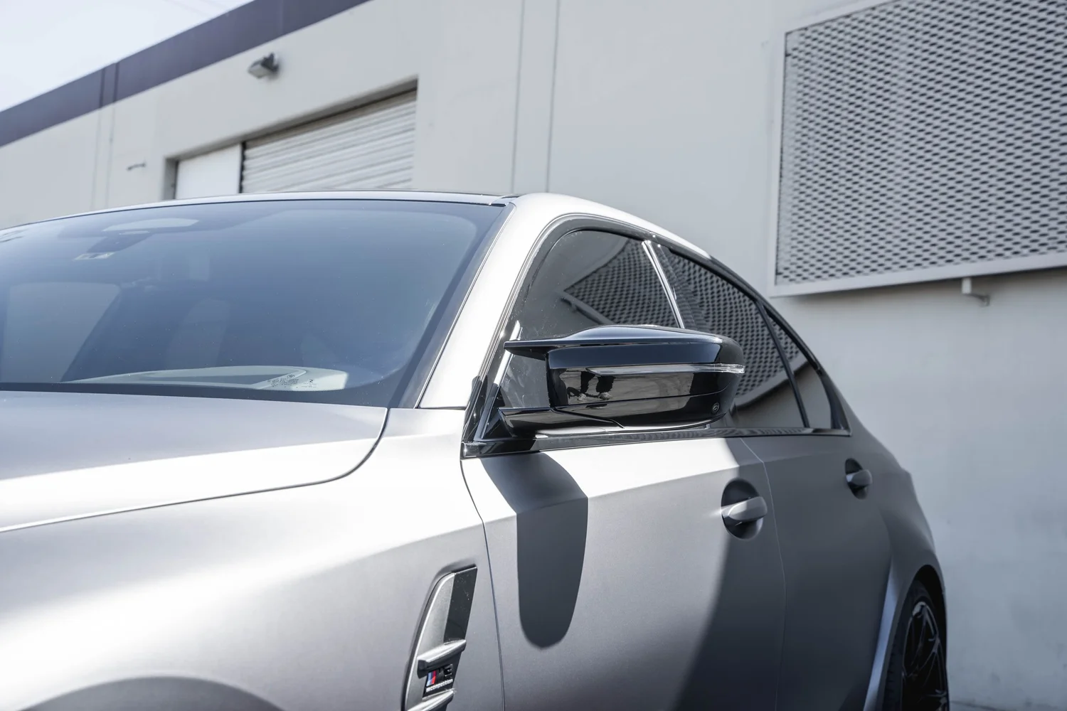 BMW M3 side-mirror and front-quarter detail after silver vinyl wrap