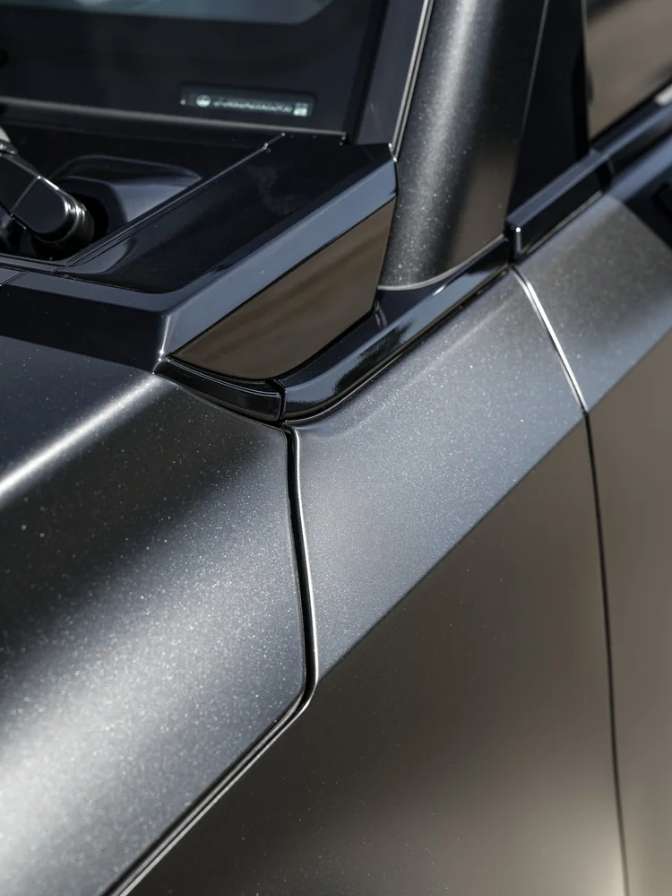 Close dark side-mirror base beside the windshield corner, sculpted front bodywork and door seam on the GX 550
