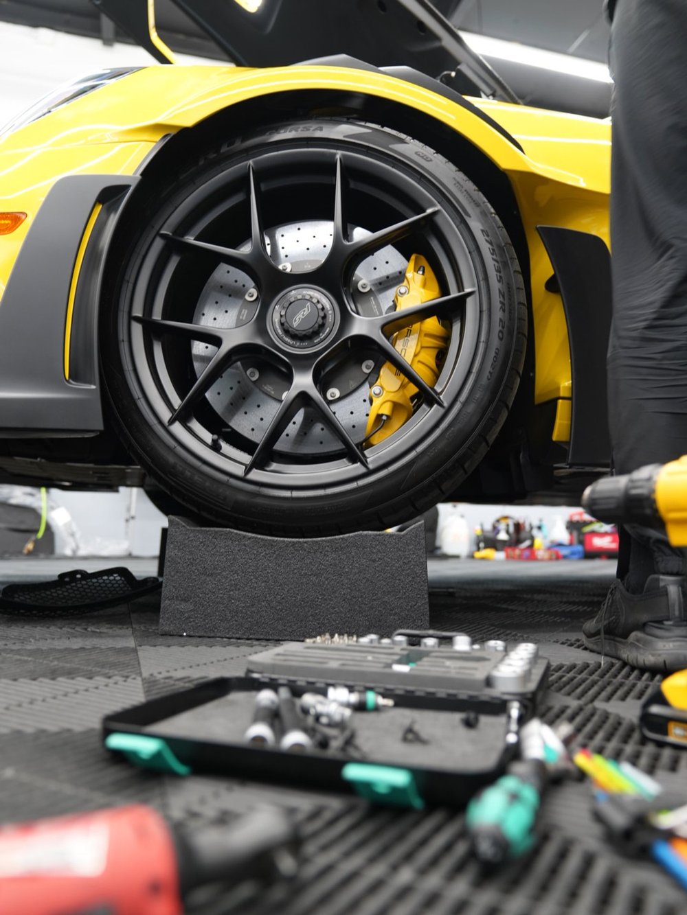 Yellow performance car raised for detailed paint protection film installation