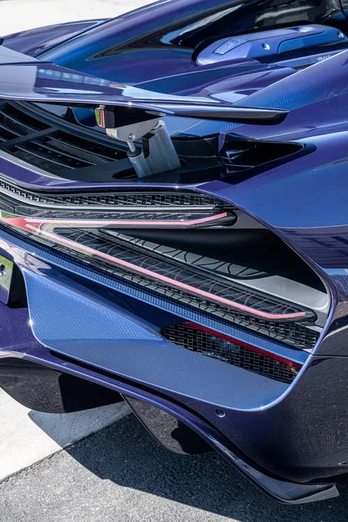 W16 Mistral rear-corner close-up showing Blue Carbon, an X-shaped taillight and the raised wing support