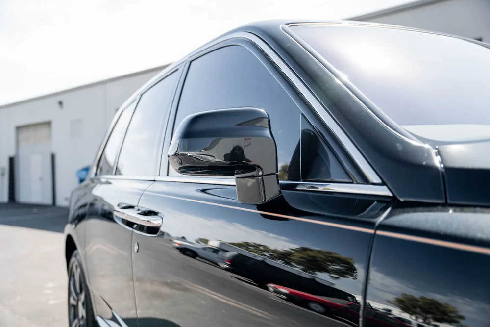 Black Rolls-Royce Cullinan with Chrome Exterior Trim — side glass, mirror and black exterior panels in a landscape detail