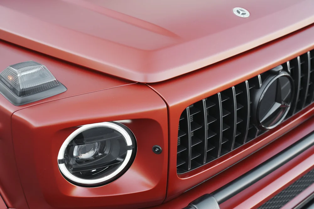 Elevated close view of the G63 red hood, fender-top marker, round headlight and black vertical grille