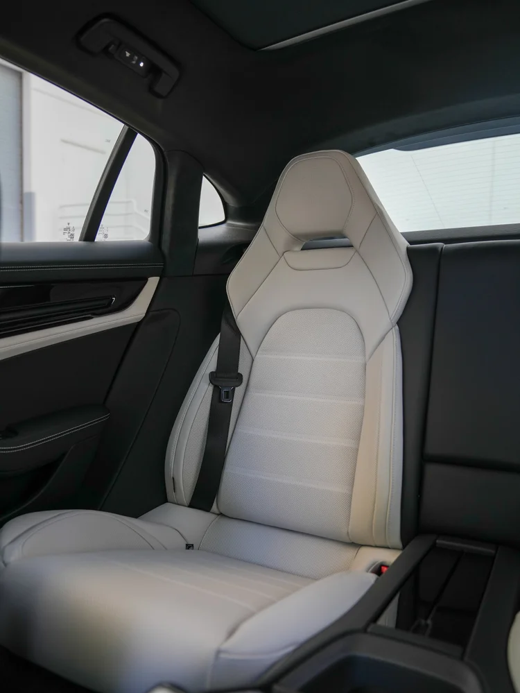 Light perforated rear seat with a crest on the headrest and a black seat belt