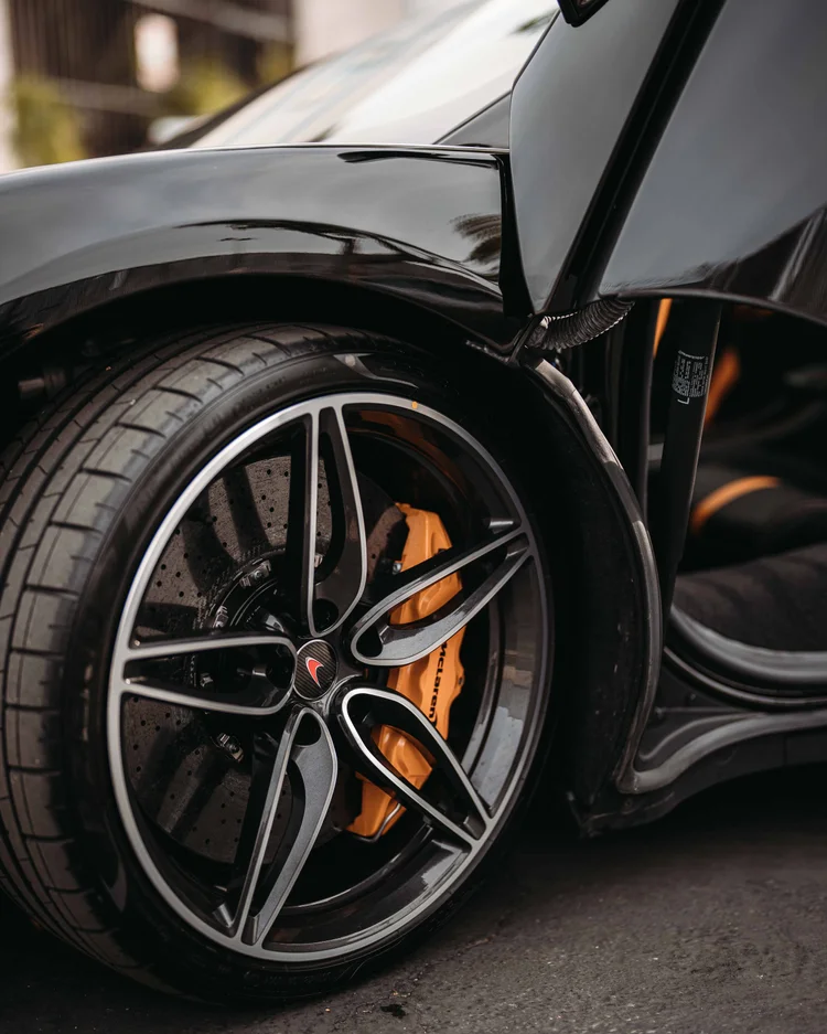 Front wheel and orange caliper beneath the raised door beside the open cabin entrance.