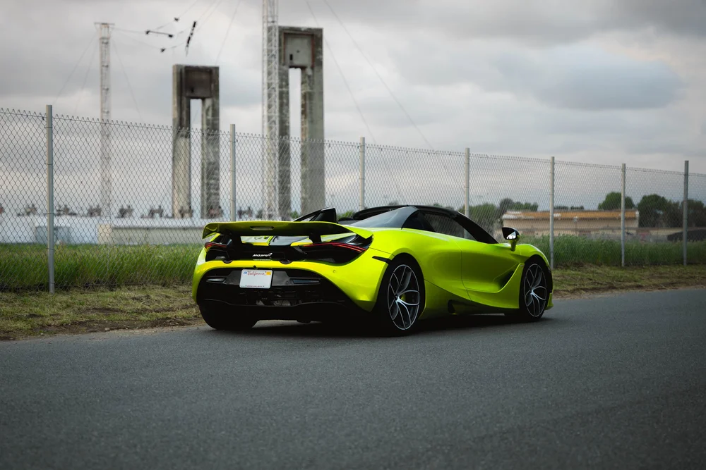 Green McLaren 720S in a complete rear three-quarter view with both wheels and the raised rear wing visible