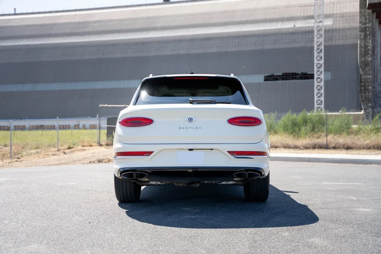 White Bentley SUV viewed straight from behind with oval red tail lamps.