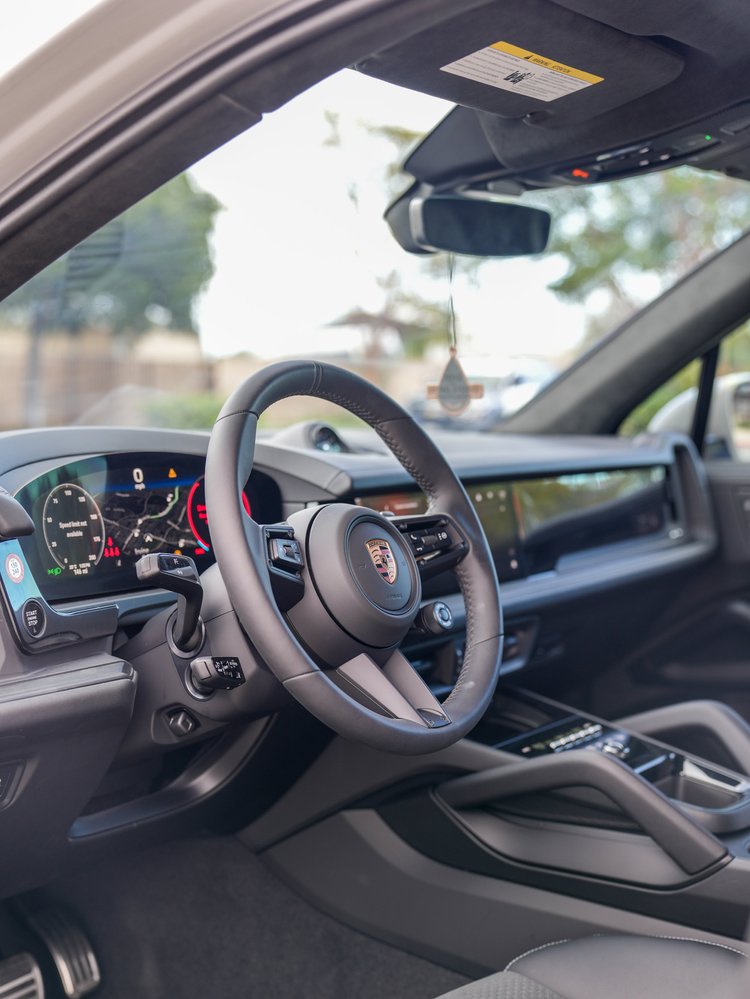 Porsche Cayenne GTS black cockpit with the steering wheel, digital instruments and center console visible.