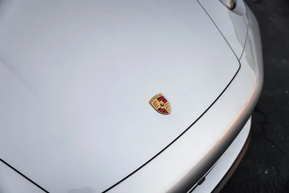 Close-up of the Porsche crest and panel seam on the Targa silver hood