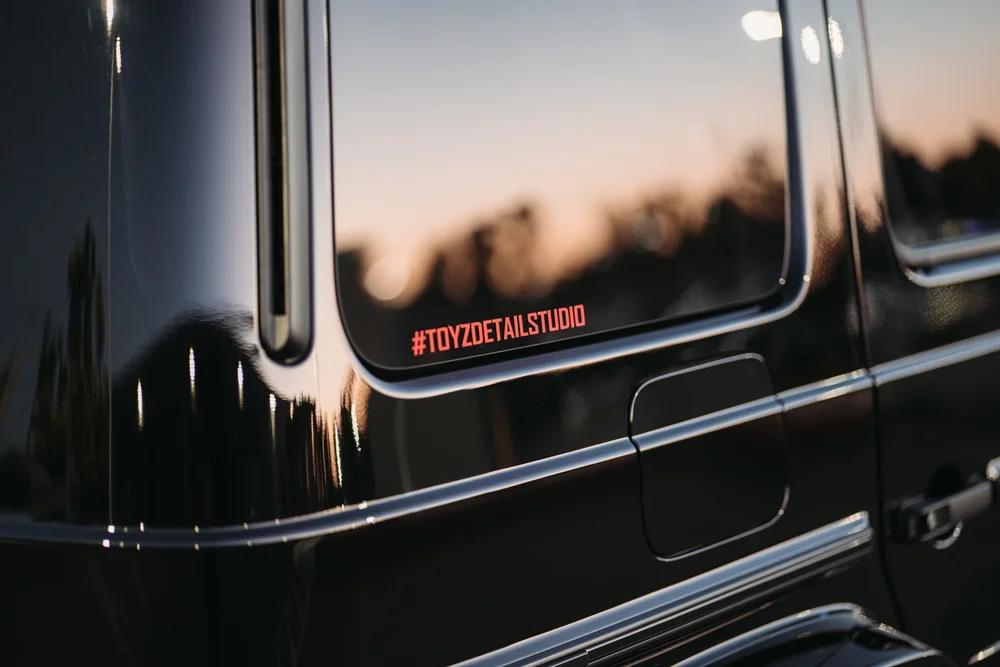 Red Toyz Detail Studio hashtag on the rear quarter window above reflective dark bodywork and a rectangular fuel door.