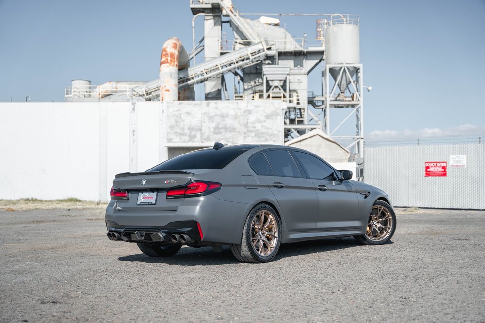 BMW M5 CS in a complete rear three-quarter view with bronze-colored wheels, dark glass and four exhaust outlets