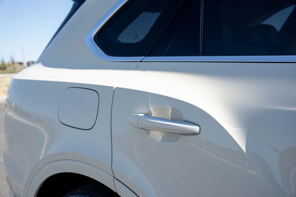 White rear door and quarter-panel detail with dark glass and a fuel door.