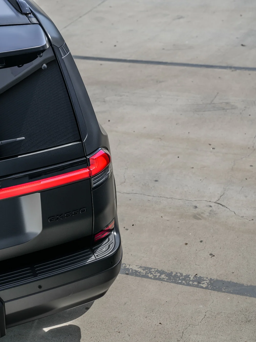 High close rear corner with GX550 lettering, the red rear light bar and part of the rear window above the dark bumper