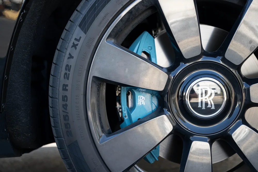 Dark Metallic Grey Rolls-Royce Cullinan — wheel-spoke faces, RR center emblem and pale-blue brake caliper