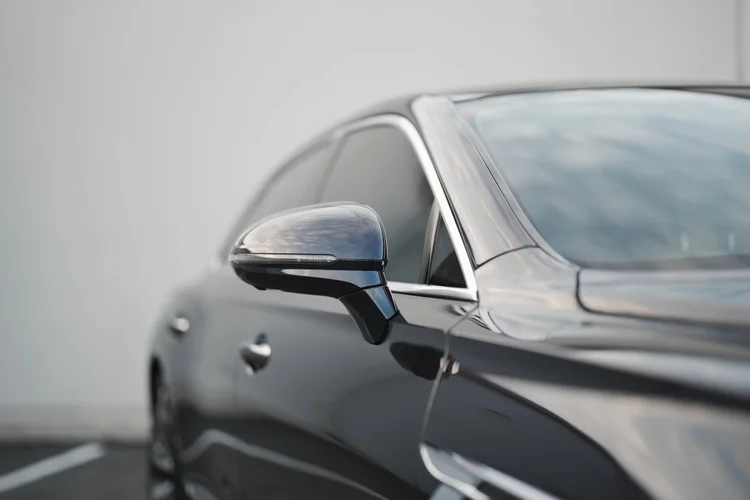 Dark side mirror and bright window surround against the pale wall.