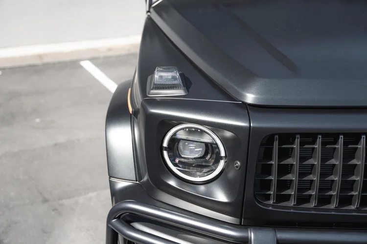 High front-corner detail of the grey G 63 hood, circular headlamp, grille and clear fender-top lamp