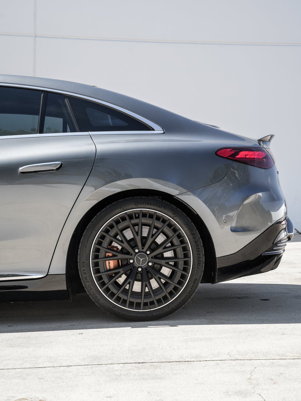 Rear wheel, quarter panel, tail lamp and rear side-glass detail on the gray Mercedes-AMG EQE 53.