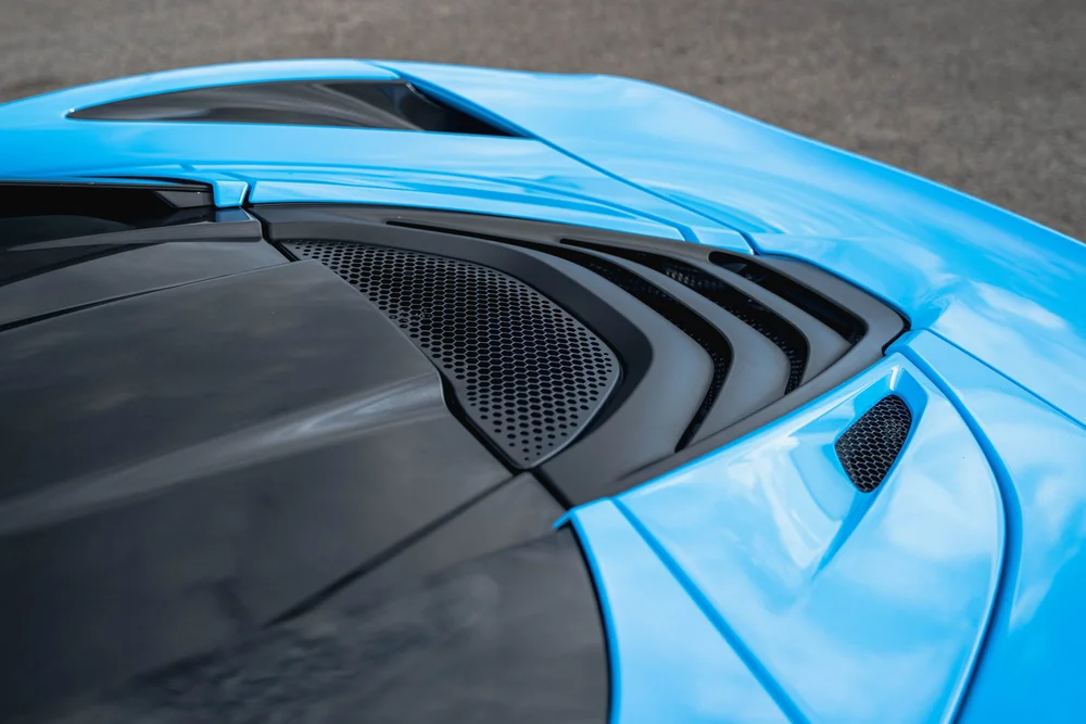 Blue McLaren 720S rear deck surrounding black louvers and a mesh vent